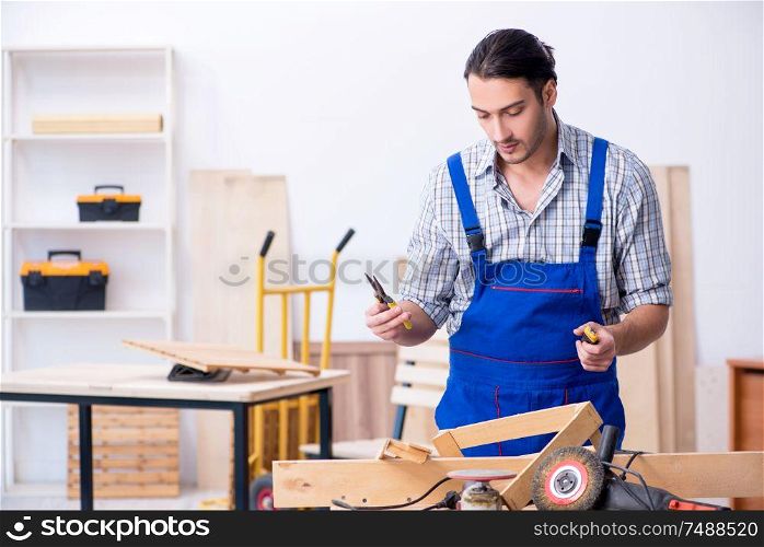 The young male carpenter working indoors . Young male carpenter working indoors