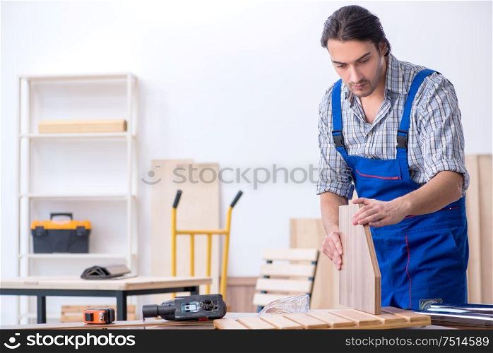 The young male carpenter working indoors. Young male carpenter working indoors