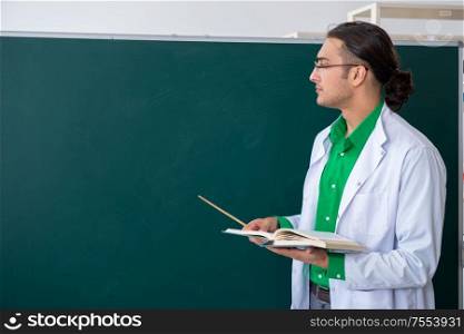 The young male chemist teacher in front of blackboard. Young male chemist teacher in front of blackboard