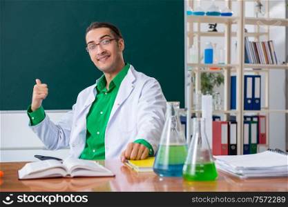 The young male chemist teacher in front of blackboard. Young male chemist teacher in front of blackboard