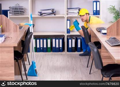 The young male contractor cleaning the office . Young male contractor cleaning the office