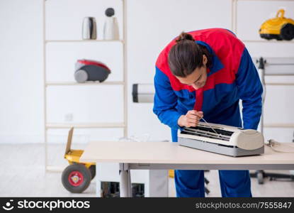 The young male contractor repairing air-conditioner at workshop. Young male contractor repairing air-conditioner at workshop