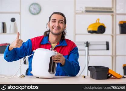 The young male contractor repairing toaster at workshop. Young male contractor repairing toaster at workshop