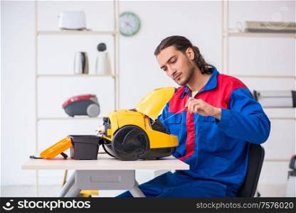 The young male contractor repairing vacuum cleaner at workshop. Young male contractor repairing vacuum cleaner at workshop