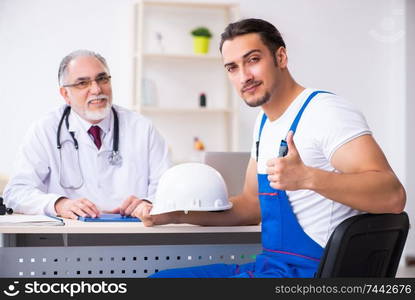 The young male contractor visiting old doctor . Young male contractor visiting old doctor 