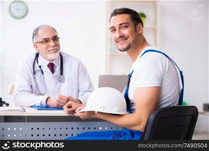 The young male contractor visiting old doctor. Young male contractor visiting old doctor