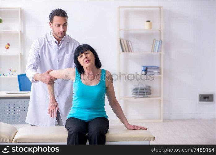 The young male doctor examining old female patient . Young male doctor examining old female patient