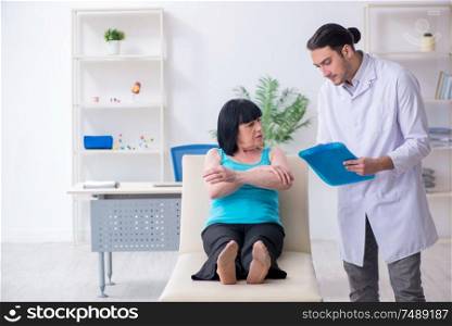 The young male doctor examining old female patient . Young male doctor examining old female patient