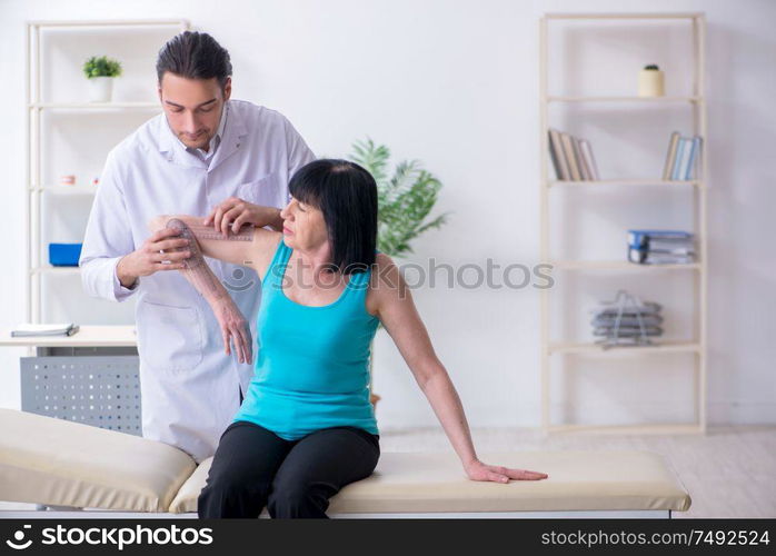 The young male doctor examining old female patient. Young male doctor examining old female patient