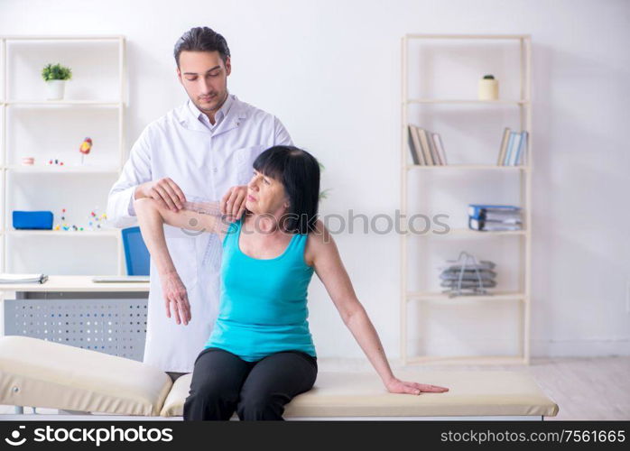 The young male doctor examining old female patient. Young male doctor examining old female patient