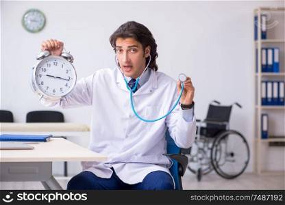 The young male doctor in time management concept . Young male doctor in time management concept