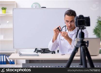 The young male doctor recording video for his blog . Young male doctor recording video for his blog