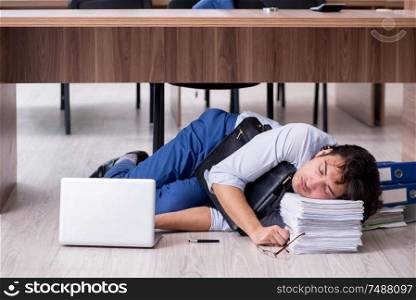 The young male employee and too many work in the office. Young male employee and too many work in the office