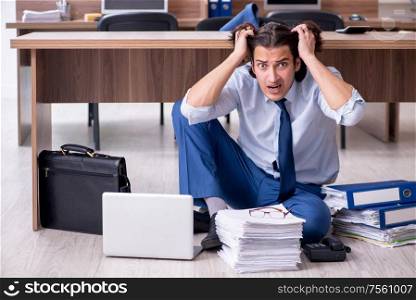 The young male employee and too many work in the office. Young male employee and too many work in the office