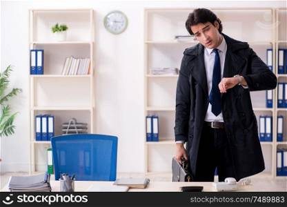 The young male employee in the office in time management concept. Young male employee in the office in time management concept