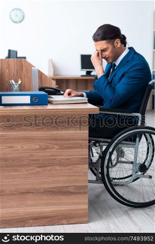 The young male employee in wheel-chair. Young male employee in wheel-chair