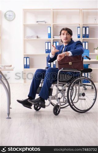 The young male employee in wheelchair working in the office. Young male employee in wheelchair working in the office