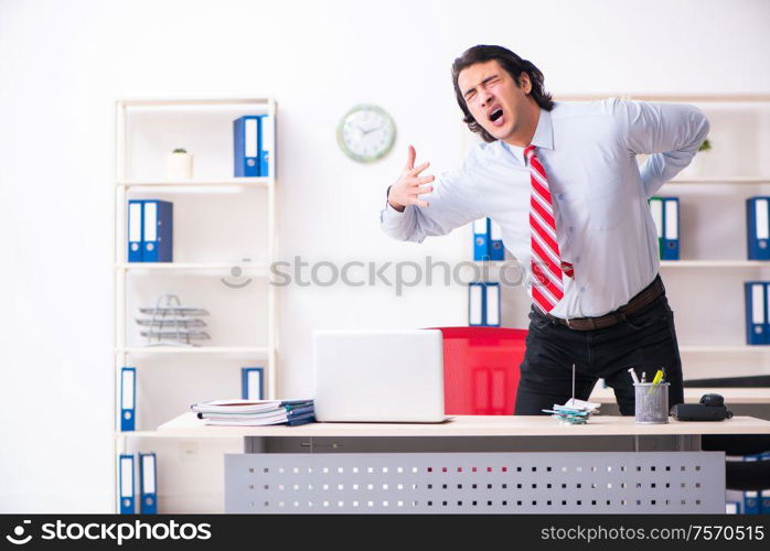 The young male employee suffering in the office. Young male employee suffering in the office