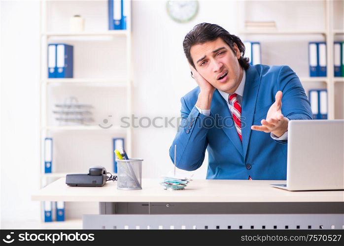 The young male employee suffering in the office. Young male employee suffering in the office