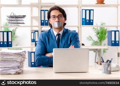 The young male employee with tape on the mouth. Young male employee with tape on the mouth