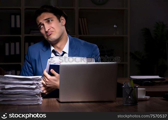 The young male employee working night in the office. Young male employee working night in the office