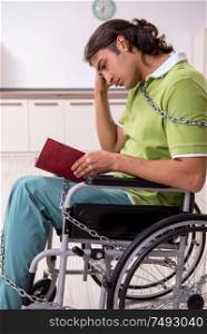 The young male invalid in wheel-chair suffering at home. Young male invalid in wheel-chair suffering at home