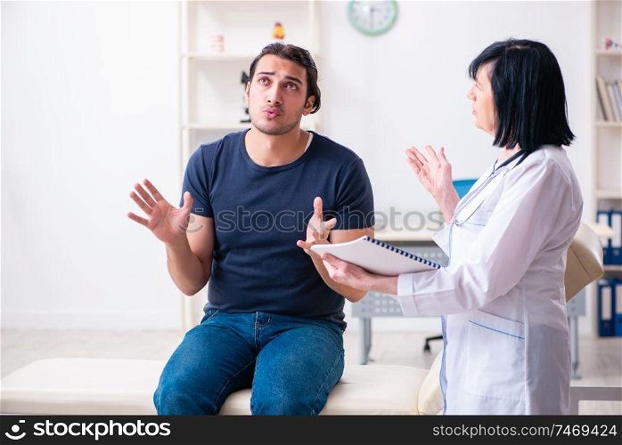 The young male patient visiting aged female doctor . Young male patient visiting aged female doctor 
