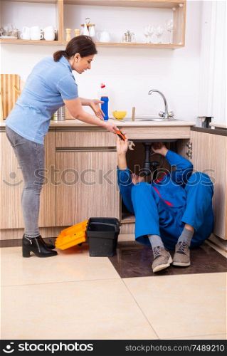 The young male repairman repairing tap . Young male repairman repairing tap