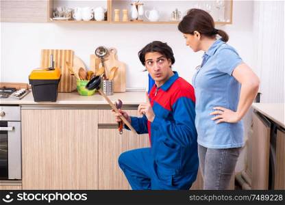 The young male repairman repairing tap. Young male repairman repairing tap