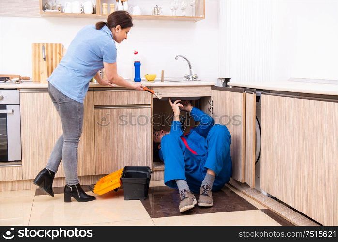 The young male repairman repairing tap. Young male repairman repairing tap
