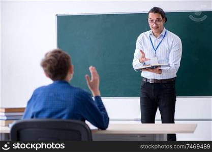 The young male teacher and boy in the classroom . Young male teacher and boy in the classroom 