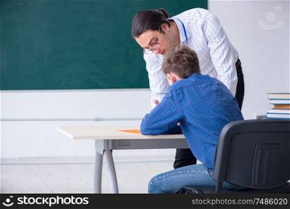 The young male teacher and boy in the classroom . Young male teacher and boy in the classroom