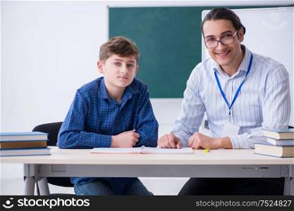 The young male teacher and boy in the classroom. Young male teacher and boy in the classroom