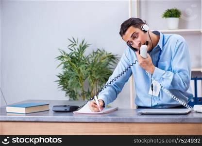 The young male travel agent working in the office. Young male travel agent working in the office