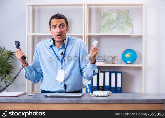 The young male travel agent working in the office. Young male travel agent working in the office