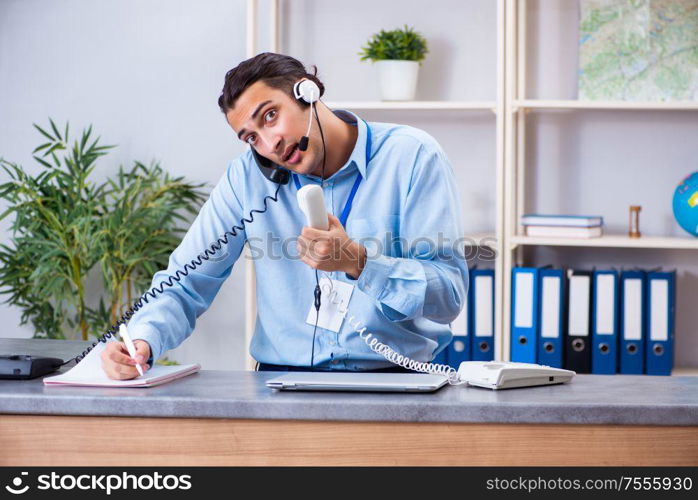 The young male travel agent working in the office. Young male travel agent working in the office