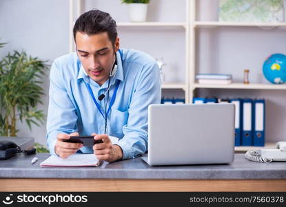 The young male travel agent working in the office. Young male travel agent working in the office