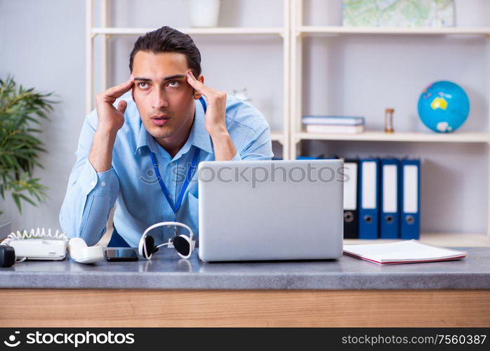 The young male travel agent working in the office. Young male travel agent working in the office