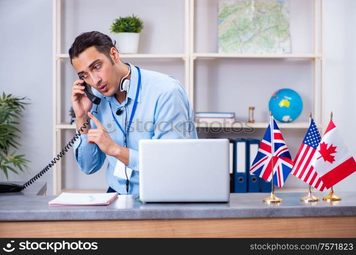 The young male travel agent working in the office. Young male travel agent working in the office