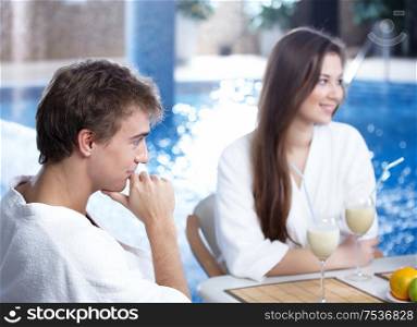 The young man and the girl in cafe against water