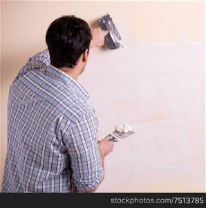 The young man applying plaster on wall at home. Young man applying plaster on wall at home
