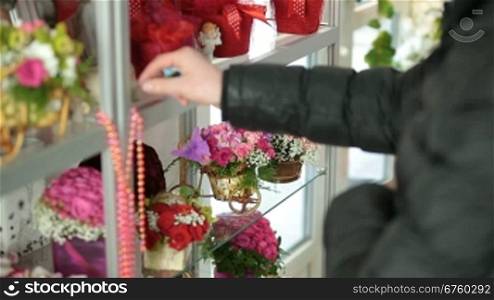 The young man choosing flower arrangement in florist shop