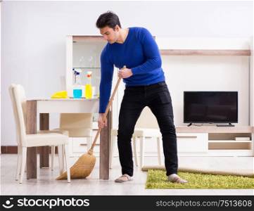 The young man cleaning floor with broom. Young man cleaning floor with broom