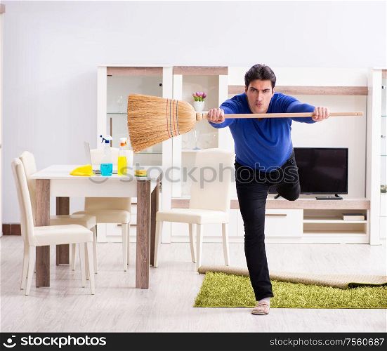 The young man cleaning floor with broom. Young man cleaning floor with broom