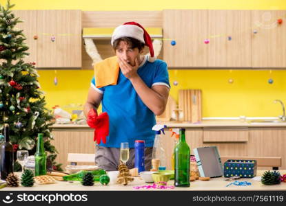 The young man cleaning kitchen after christmas party. Young man cleaning kitchen after Christmas party