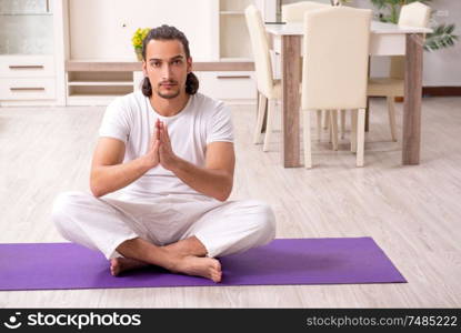 The young man doing physical exercises at home. Young man doing physical exercises at home