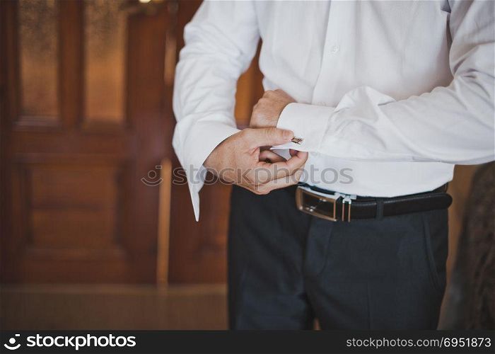 The young man dresses a shirt 1409.. Process of a N?loathing of a button on shirt sleeves.