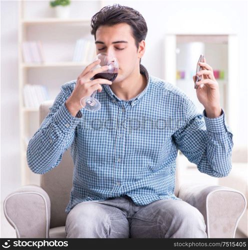 The young man drinking wine at home. Young man drinking wine at home