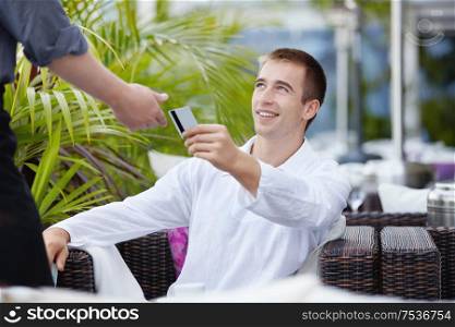 The young man gives the waiter a credit card