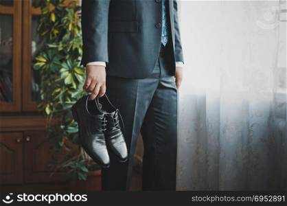 The young man holds shoes.